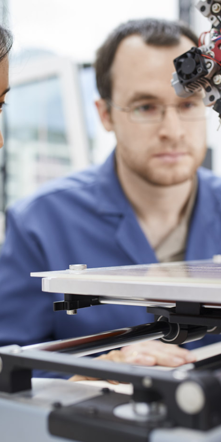 Zwei Forschende vor einem 3D-Drucker in einem Labor