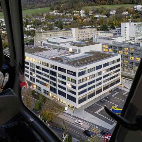 Blick aus einem Helikopter auf das weitläufige Areal des Kantonsspitals Graubünden mit mehreren Gebäuden am Churer Stadtrand.