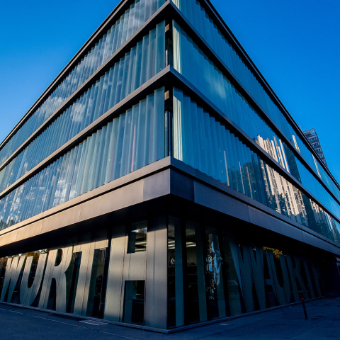 Würth: Modernes Gebäude mit blauer Glasfassade und metallischer Verkleidung, Würth-Schriftzug an der Eingangsfassade, unter klarem Himmel.