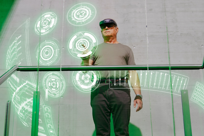 Mann nutzt eine Mixed-Reality-Brille und interagiert mit virtuellen Bedienelementen in einer modernen Arbeitsumgebung.