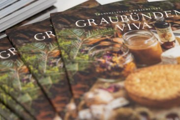 Mehrere Exemplare des kulinarischen Reiseführers «Graubünden Viva» zeigen auf dem Titel regionale Spezialitäten und Produkte aus Graubünden.